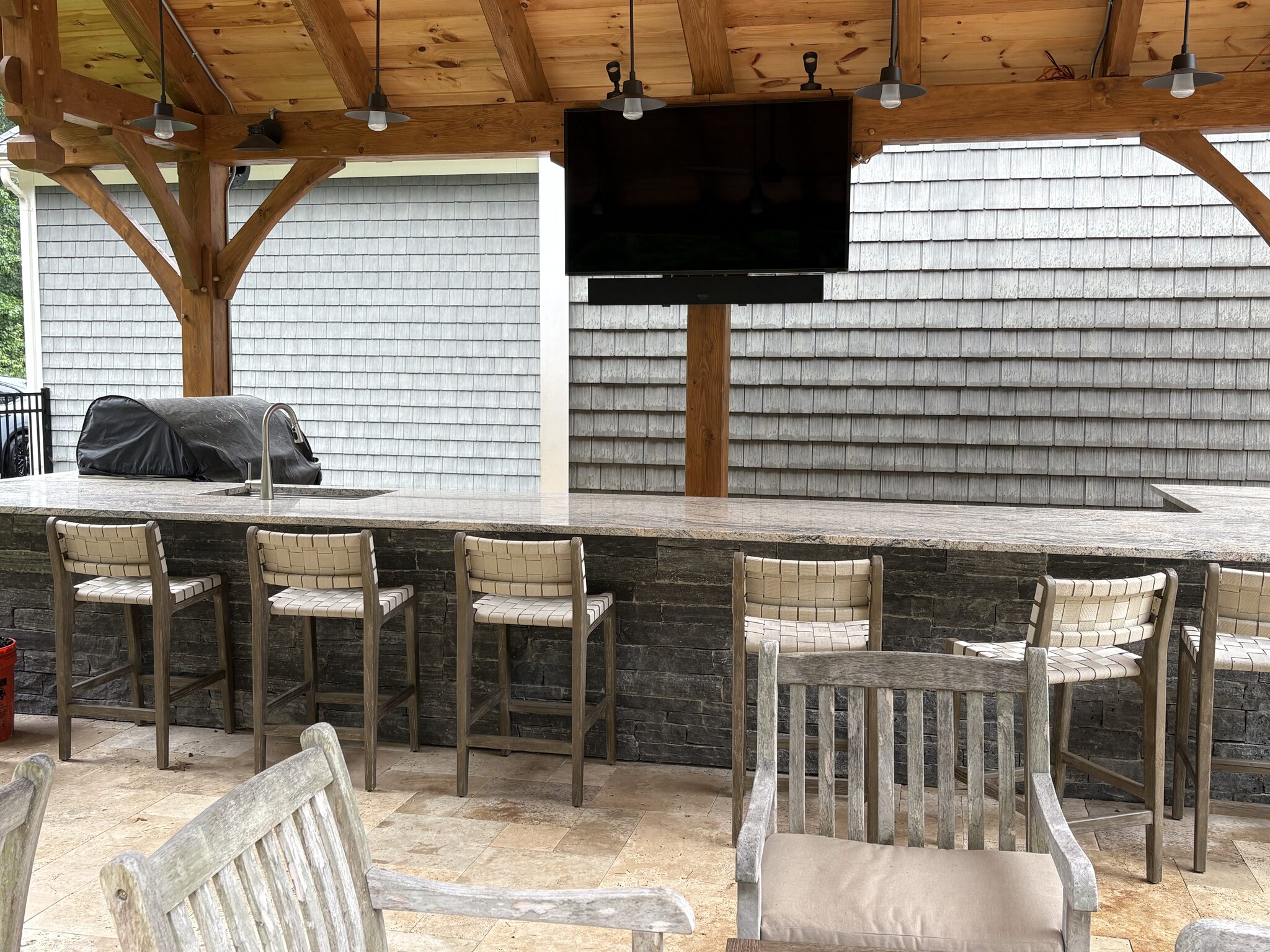 Outdoor TV installation over a stone bar and outdoor kitchen in Oakham, MA by J&S Audio Video Solutions