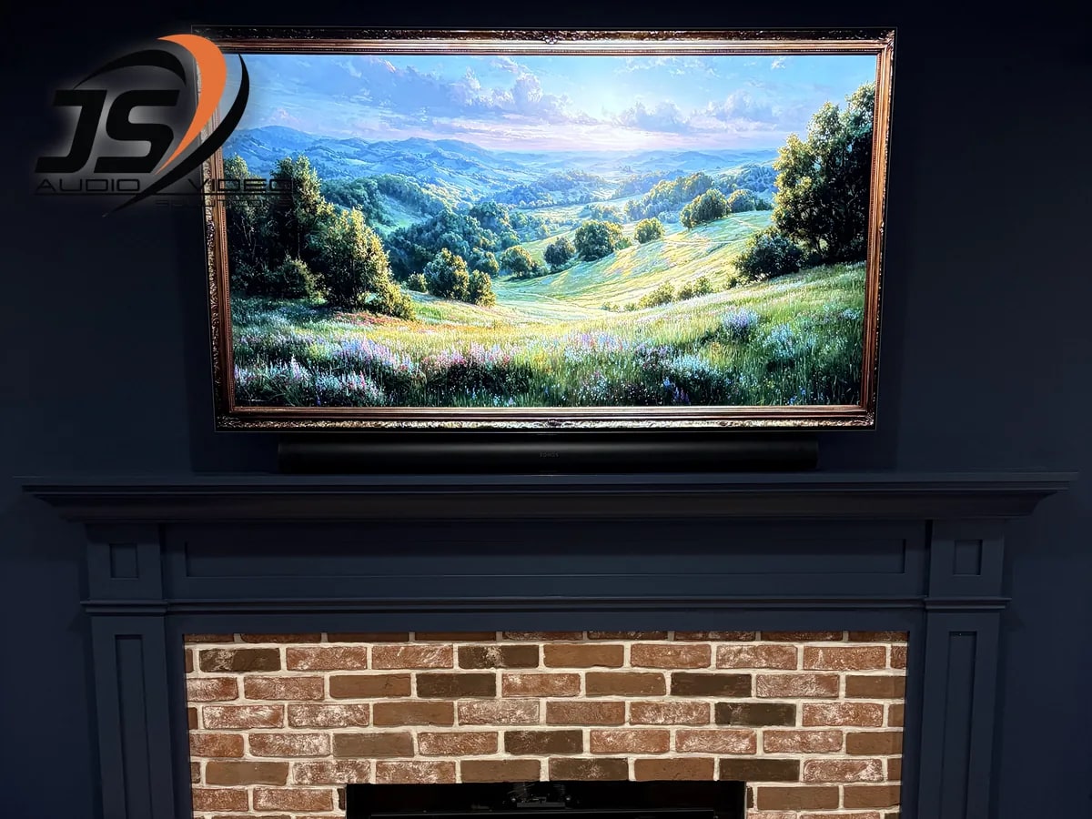 Framed television and soundbar installed above a brick fireplace in Shrewsbury, MA by J&S Audio Video Solutions