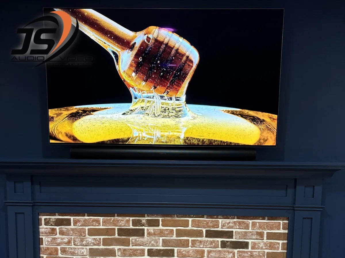 Large television and soundbar installed above a brick fireplace in Shrewsbury, MA by J&S Audio Video Solutions