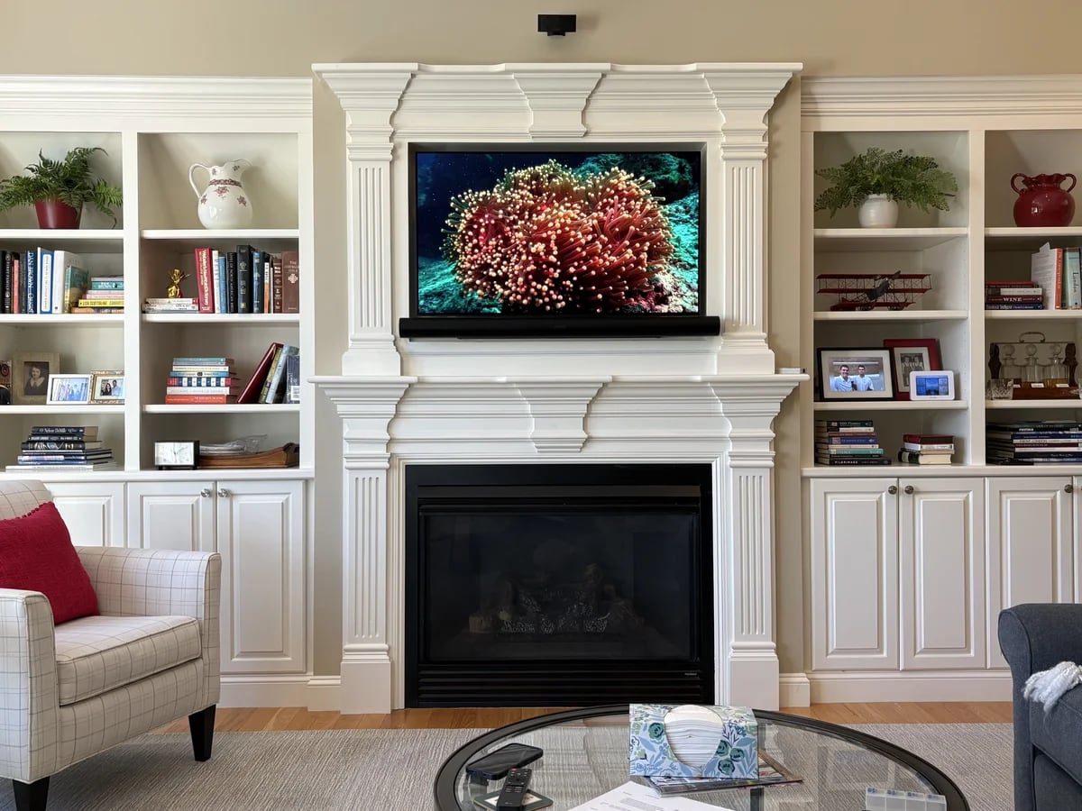 Home theater display set into custom bookcases beside a fireplace in Shrewsbury, MA by J&S Audio Video Solutions